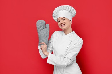 Professional chef with oven glove on red background