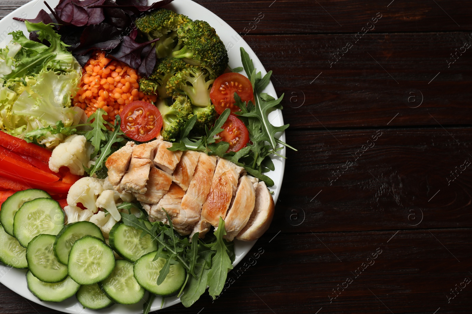 Photo of Balanced diet and healthy foods. Plate with different delicious products on wooden table, top view. Space for text