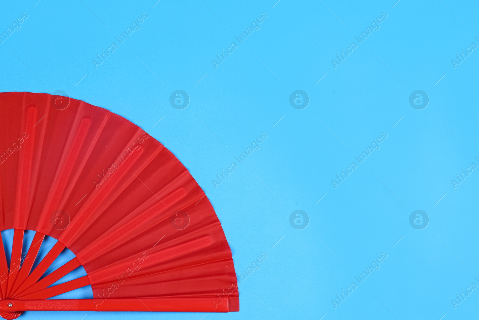 Photo of Red hand fan on light blue background, top view. Space for text