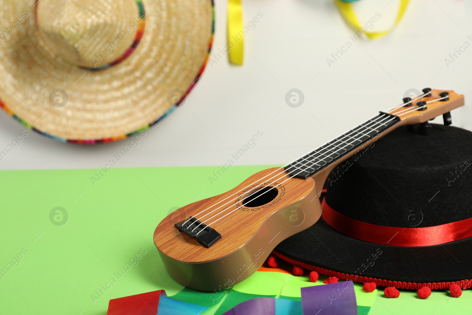 Photo of Black Flamenco hat and ukulele on green table, closeup. Space for text