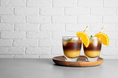 Photo of Tasty refreshing drink with coffee and orange juice on grey table, space for text