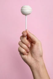 Woman holding sweet cake pop on pink background, closeup