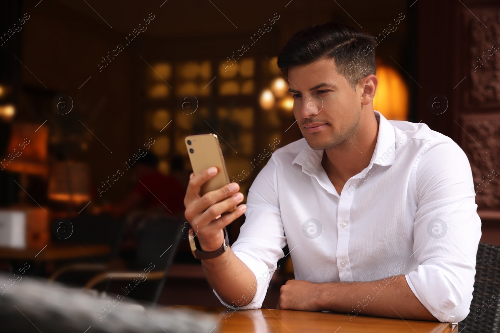 Photo of Man unlocking smartphone with facial scanner in cafe. Biometric verification