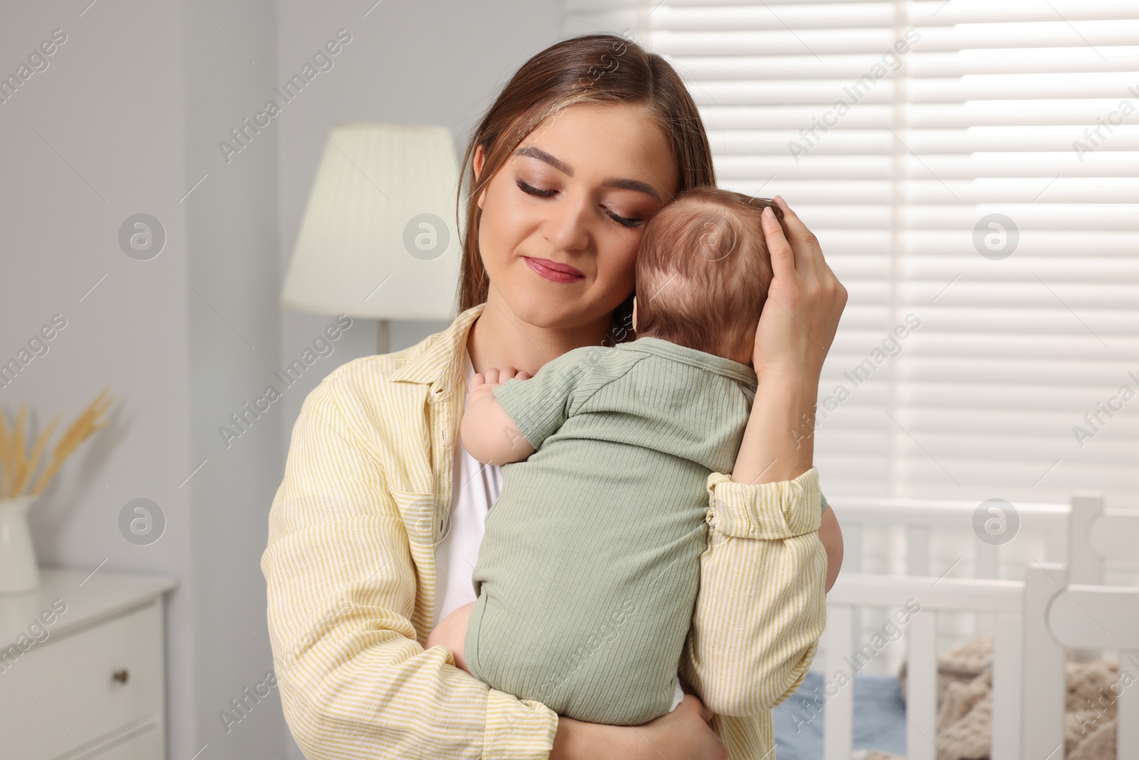 Photo of Mother holding her cute newborn baby in child's room