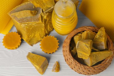 Photo of Different natural beeswax blocks and jar of honey on white wooden table, above view