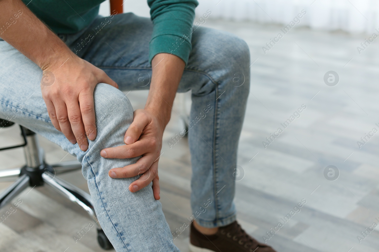 Photo of Man suffering from leg pain indoors, closeup