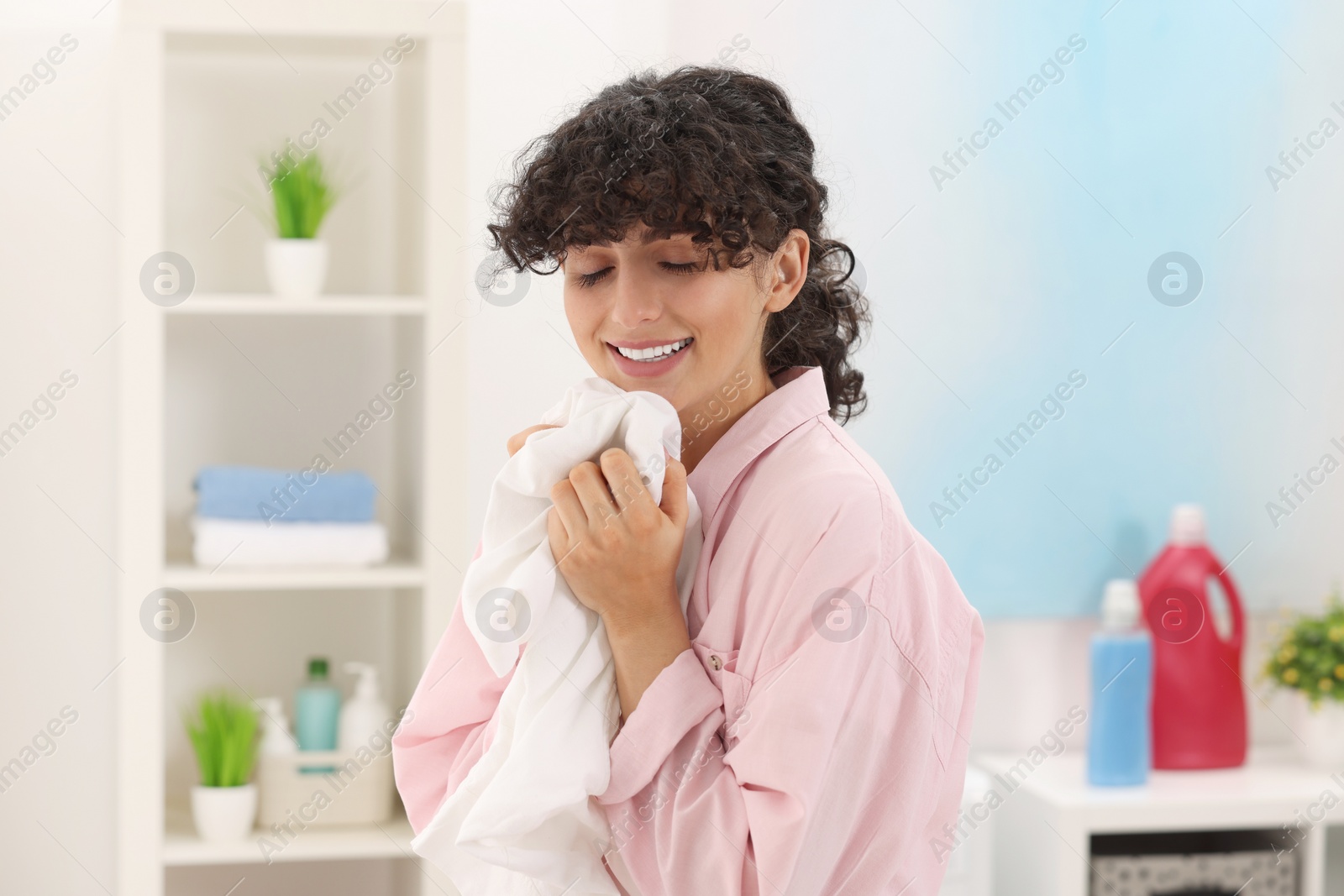 Photo of Beautiful woman with clean laundry at home