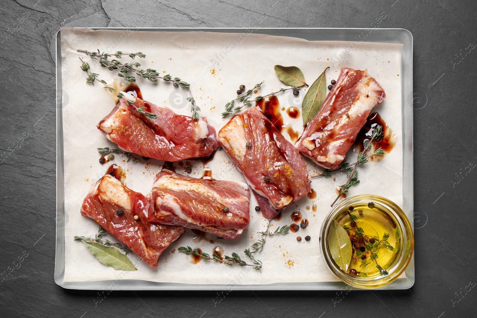 Photo of Raw marinated ribs on black table, top view