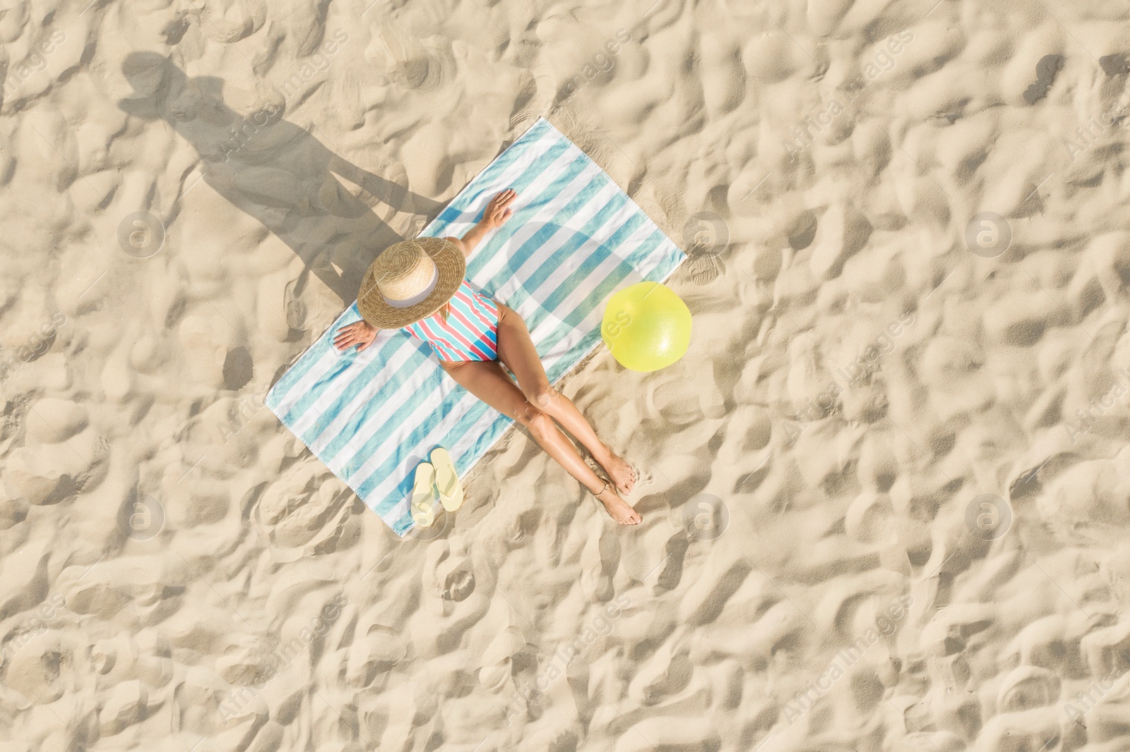 Image of Woman sunbathing on beach towel at sandy coast, aerial view