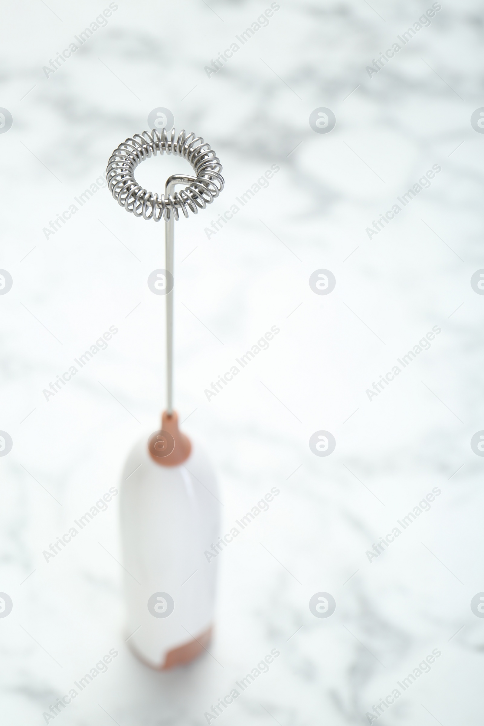 Photo of Milk frother wand on white marble table, closeup