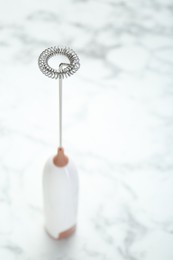 Photo of Milk frother wand on white marble table, closeup