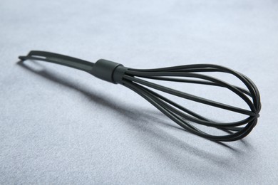 Plastic whisk on gray table, closeup. Kitchen tool