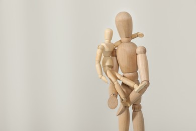 Photo of Wooden mannequins of parent with child on light background, space for text. Family Day