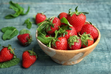 Bowl with ripe red strawberries and mint on wooden table