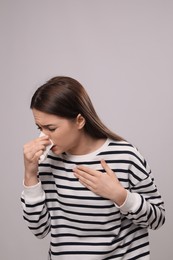 Photo of Woman blowing nose on light grey background. Cold symptoms