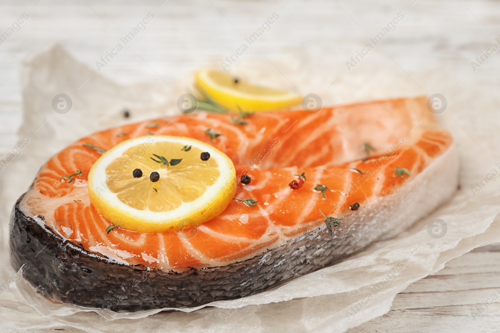 Photo of Fresh raw salmon steak with lemon and pepper on table, closeup