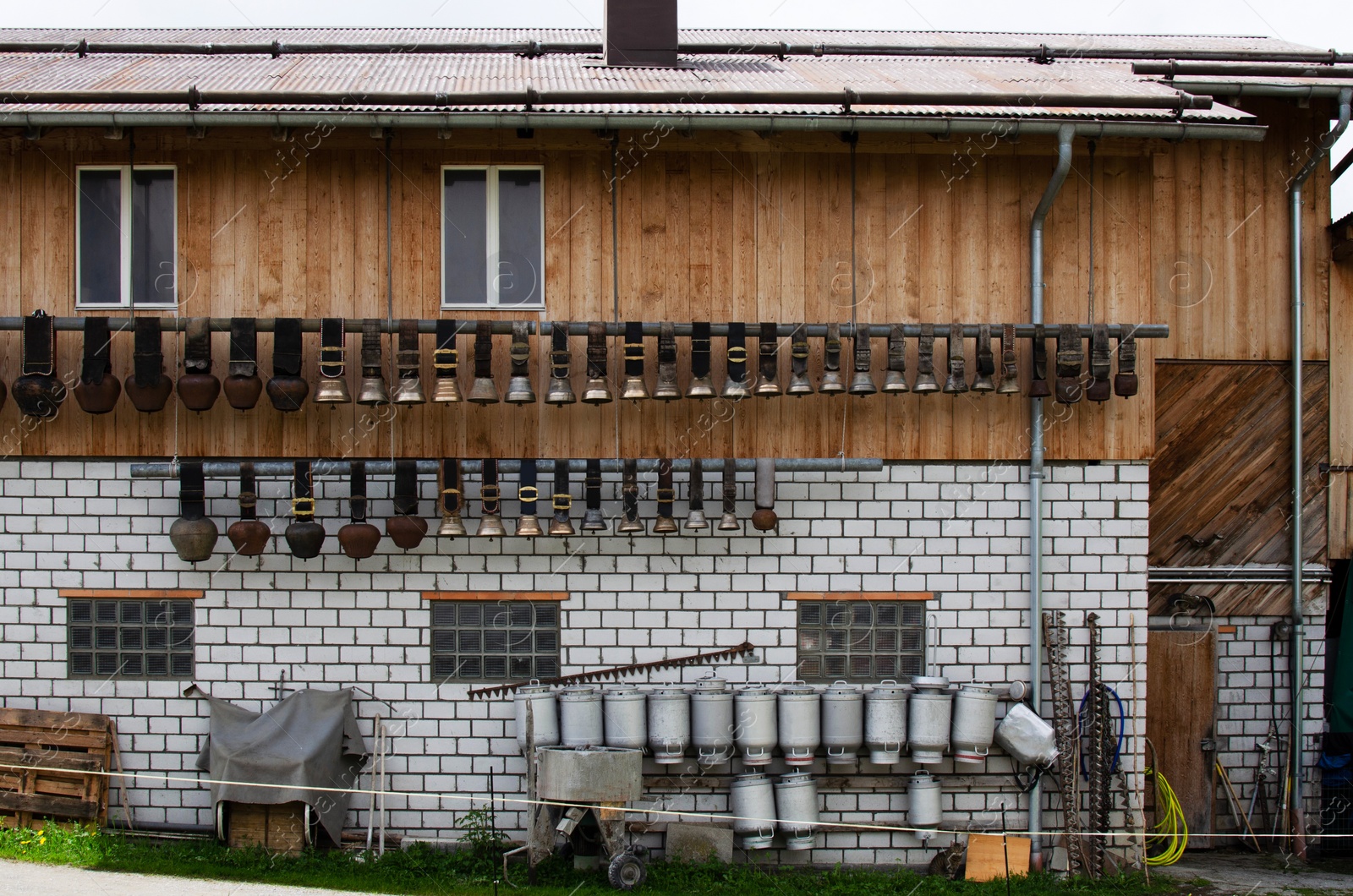 Photo of Exterior of farmer`s house with milk cans and bells for cows on wall