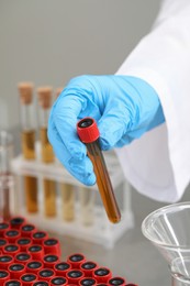 Scientist holding test tube with brown liquid, closeup