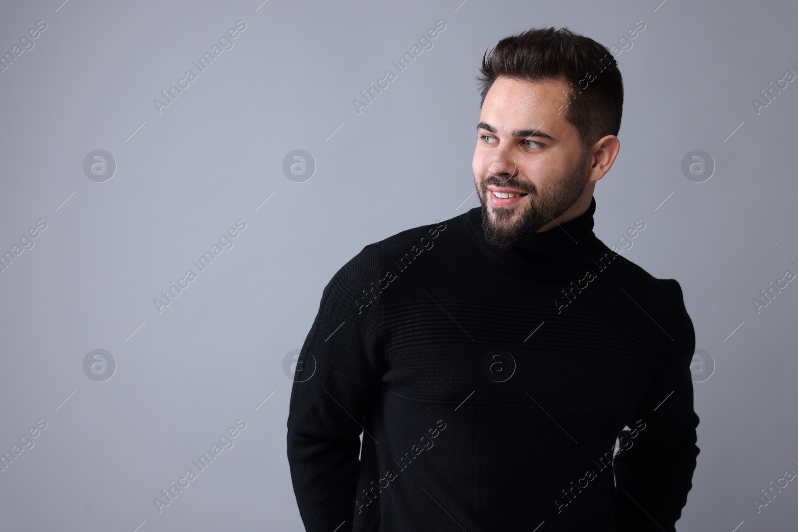 Photo of Happy man in stylish black sweater on grey background, space for text