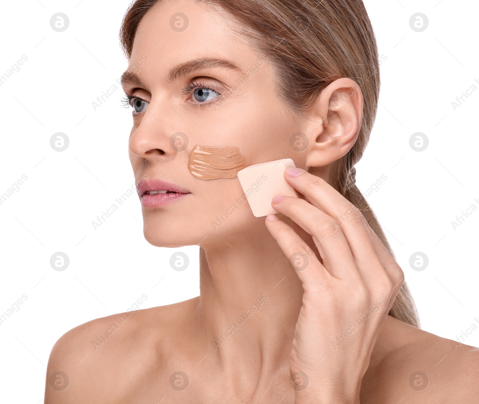 Photo of Woman applying foundation on face with makeup sponge against white background