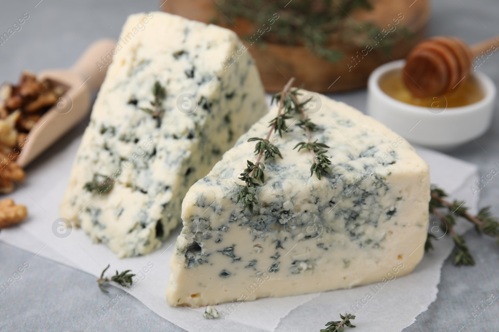 Photo of Tasty blue cheese with thyme on grey table, closeup