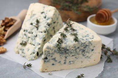 Photo of Tasty blue cheese with thyme on grey table, closeup