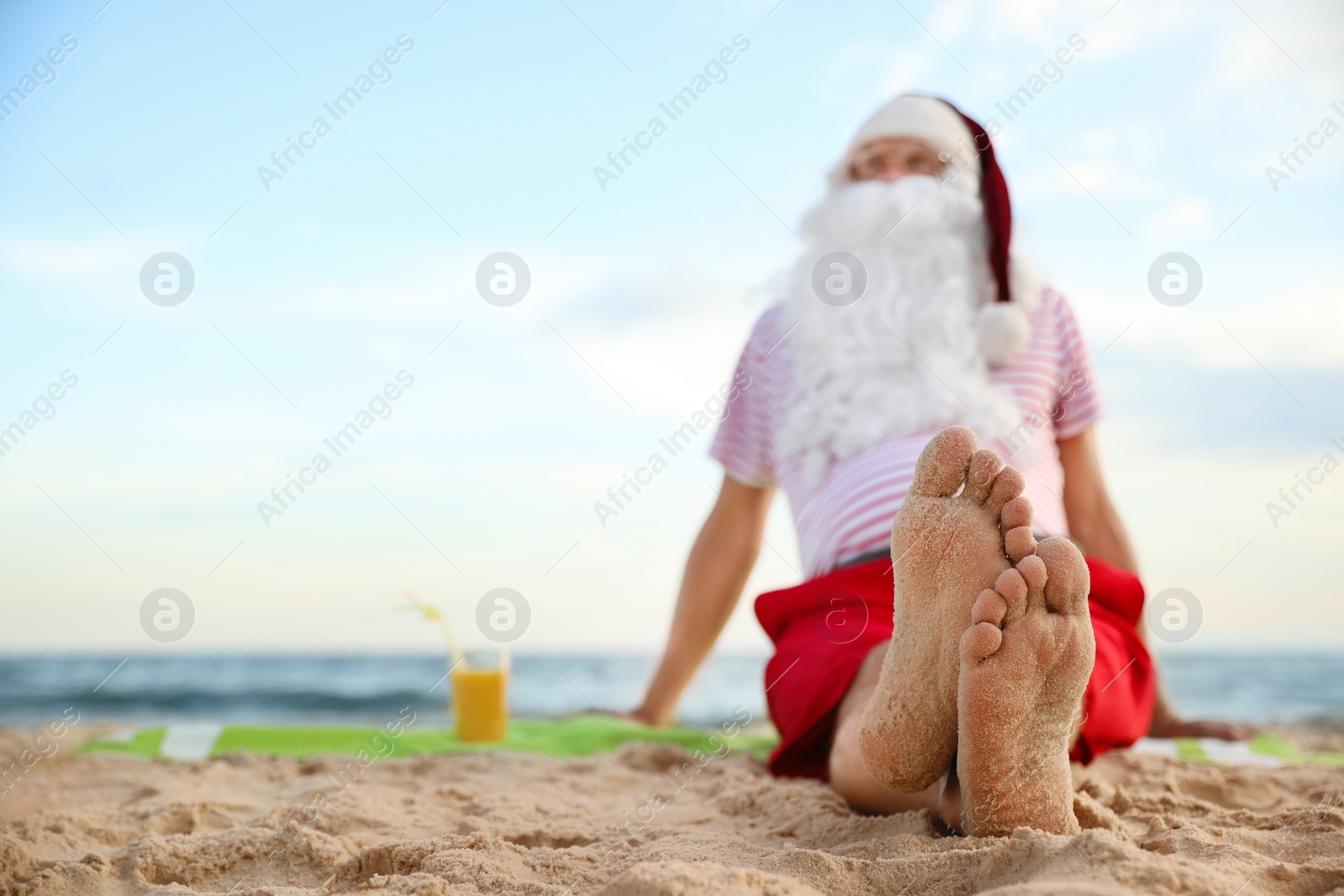 Photo of Santa Claus with cocktail relaxing on beach, space for text. Christmas vacation