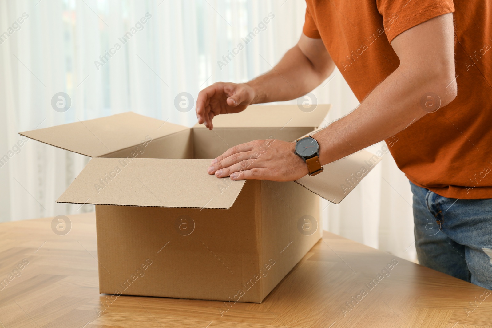 Photo of Man opening parcel at home, closeup. Internet shopping