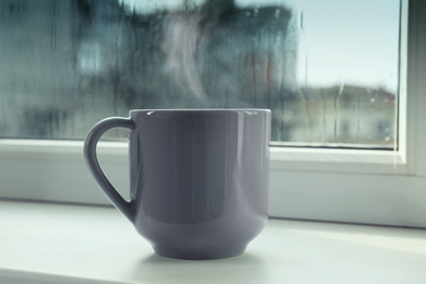 Image of Cup of hot drink near window on rainy day