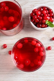 Photo of Tasty cranberry juice in glasses and fresh berries on white wooden table, flat lay