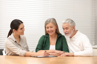 Notary showing senior couple where to sign Last Will and Testament in office