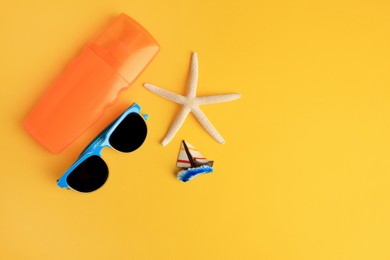 Flat lay composition with bottle of sunscreen on yellow background. Space for text