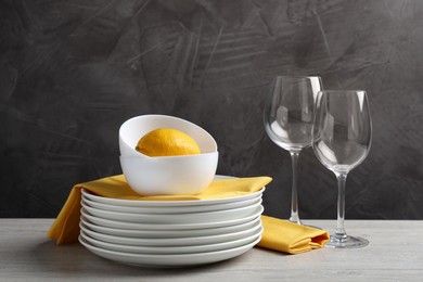 Photo of Set of clean dishware, glasses and lemon on light wooden table