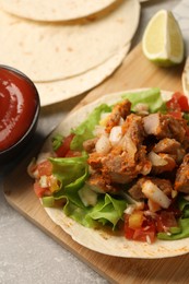Photo of Delicious tacos with vegetables and meat on grey textured table, closeup