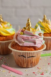 Photo of Cute sweet unicorn cupcakes on beige table, closeup