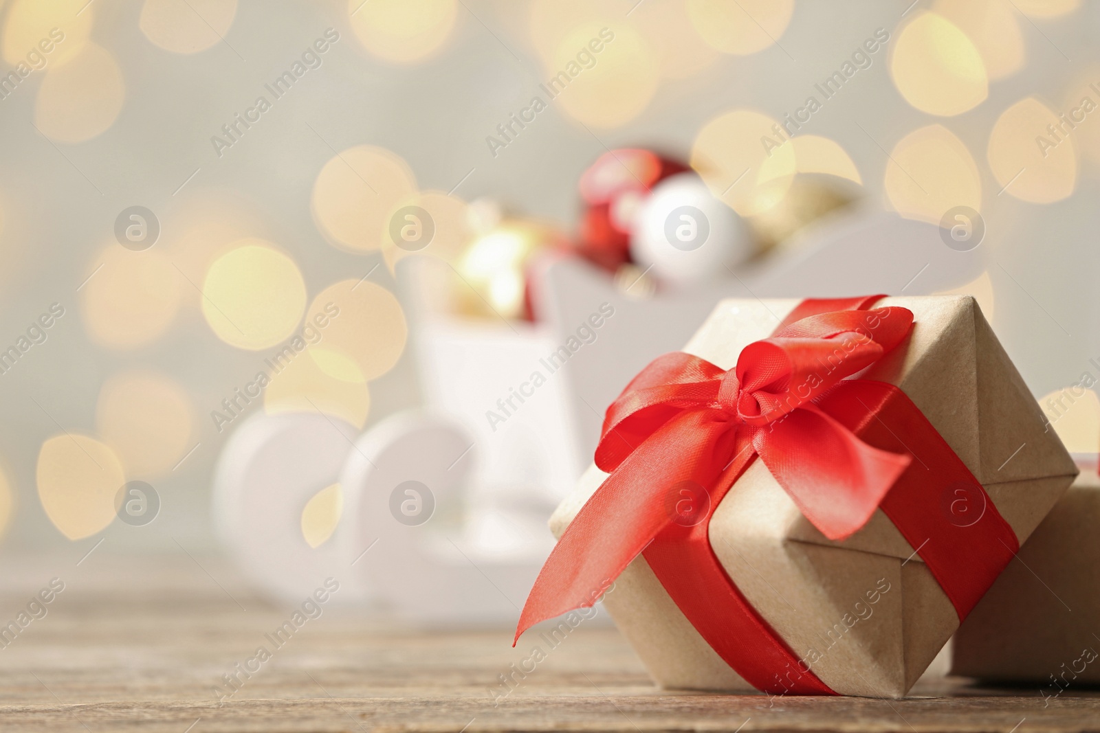 Photo of Gift box on table against blurred Christmas lights. Space for text