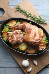 Photo of Tasty cooked rabbit with vegetables in baking dish on grey wooden table, top view