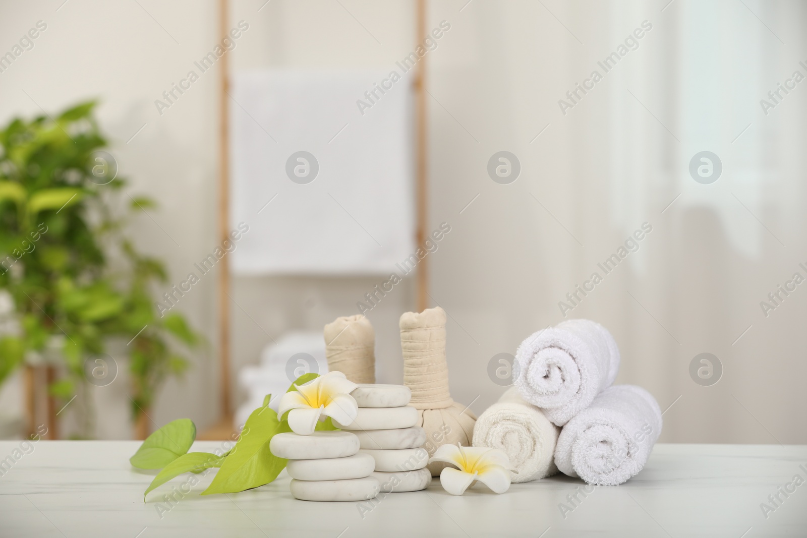 Photo of Composition with different spa products and plumeria flowers on white marble table indoors, space for text