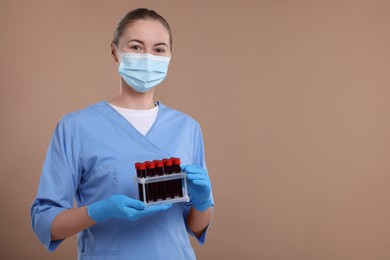 Laboratory testing. Doctor with blood samples in tubes on light brown background, space for text