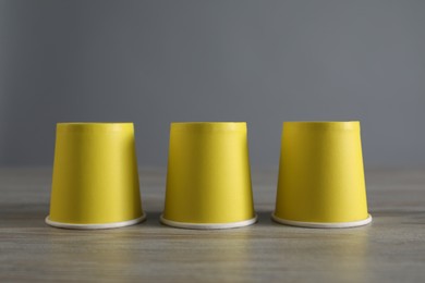Photo of Shell game. Three yellow cups on wooden table