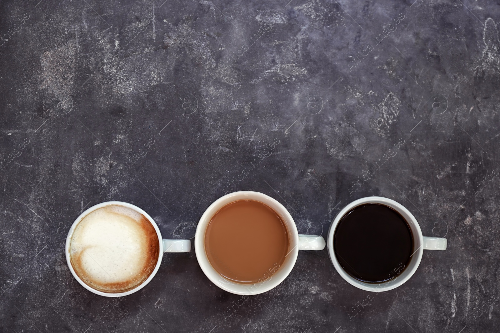 Photo of Cups of fresh aromatic coffee on grey background, top view