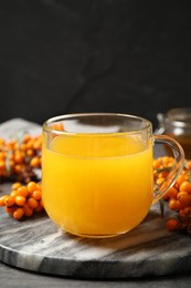 Photo of Delicious sea buckthorn tea and fresh berries on grey table