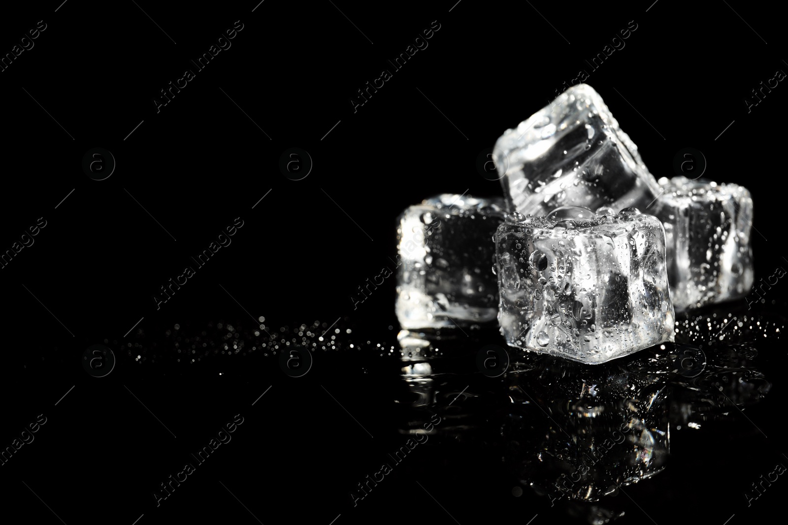 Photo of Pile of crystal clear ice cubes on black background. Space for text