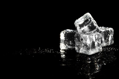 Pile of crystal clear ice cubes on black background. Space for text