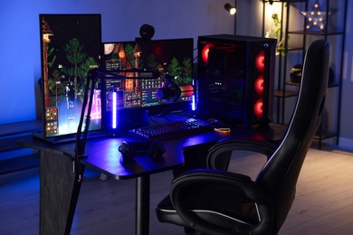 Photo of Playing video games. Stylish room interior with modern computer and gaming chair in neon lights