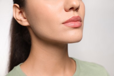 Photo of Woman with herpes on lips against light grey background, closeup