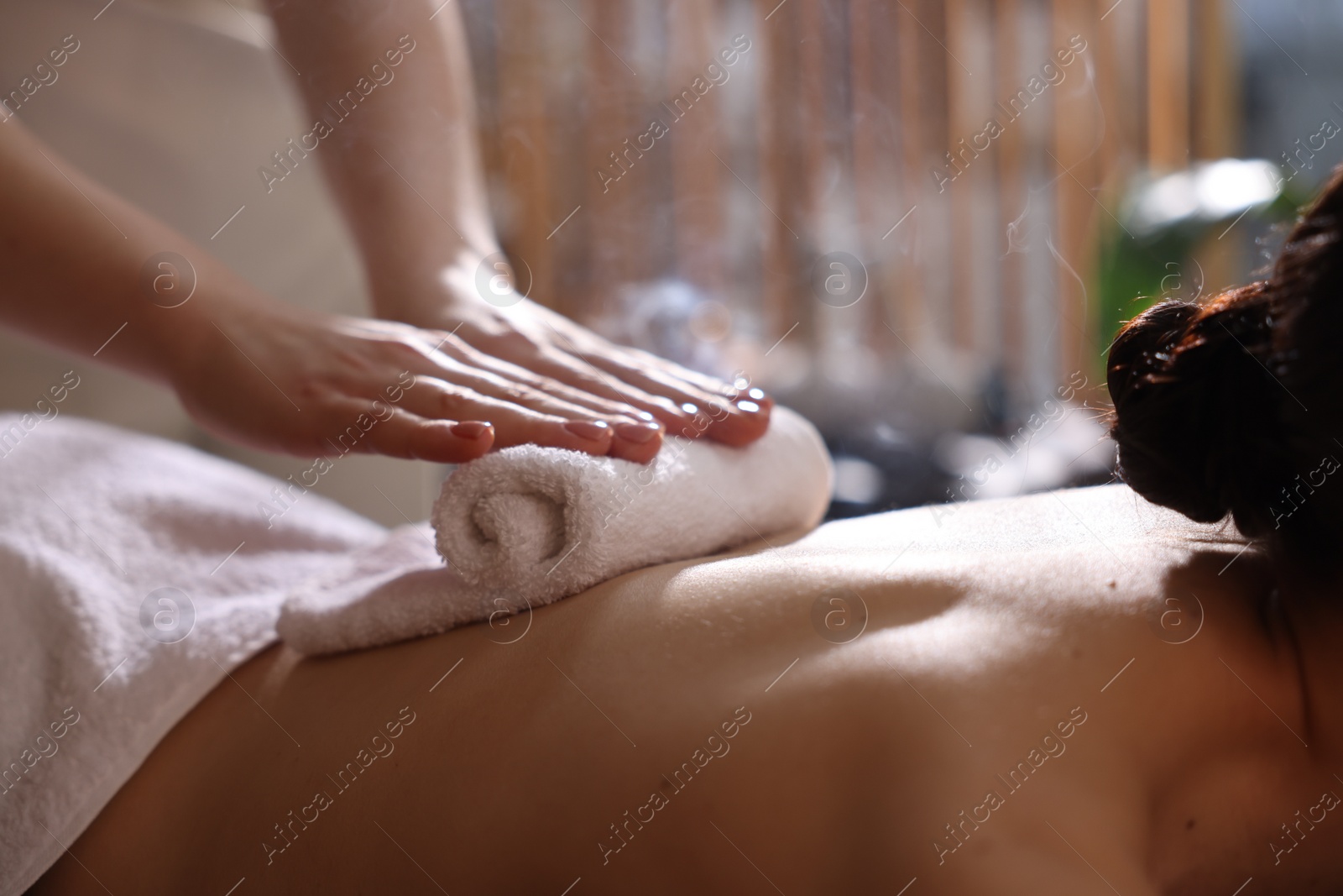 Photo of Spa therapy. Beautiful young woman lying on table during hot towel massage in salon, closeup