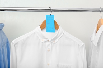 Photo of Rack with clean clothes after dry-cleaning on hangers