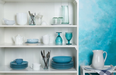 Photo of White shelving unit with set of dishware near color wall