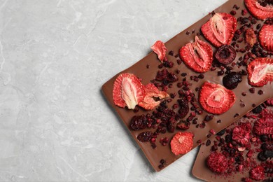 Photo of Chocolate bars with freeze dried berries on grey marble table, closeup. Space for text